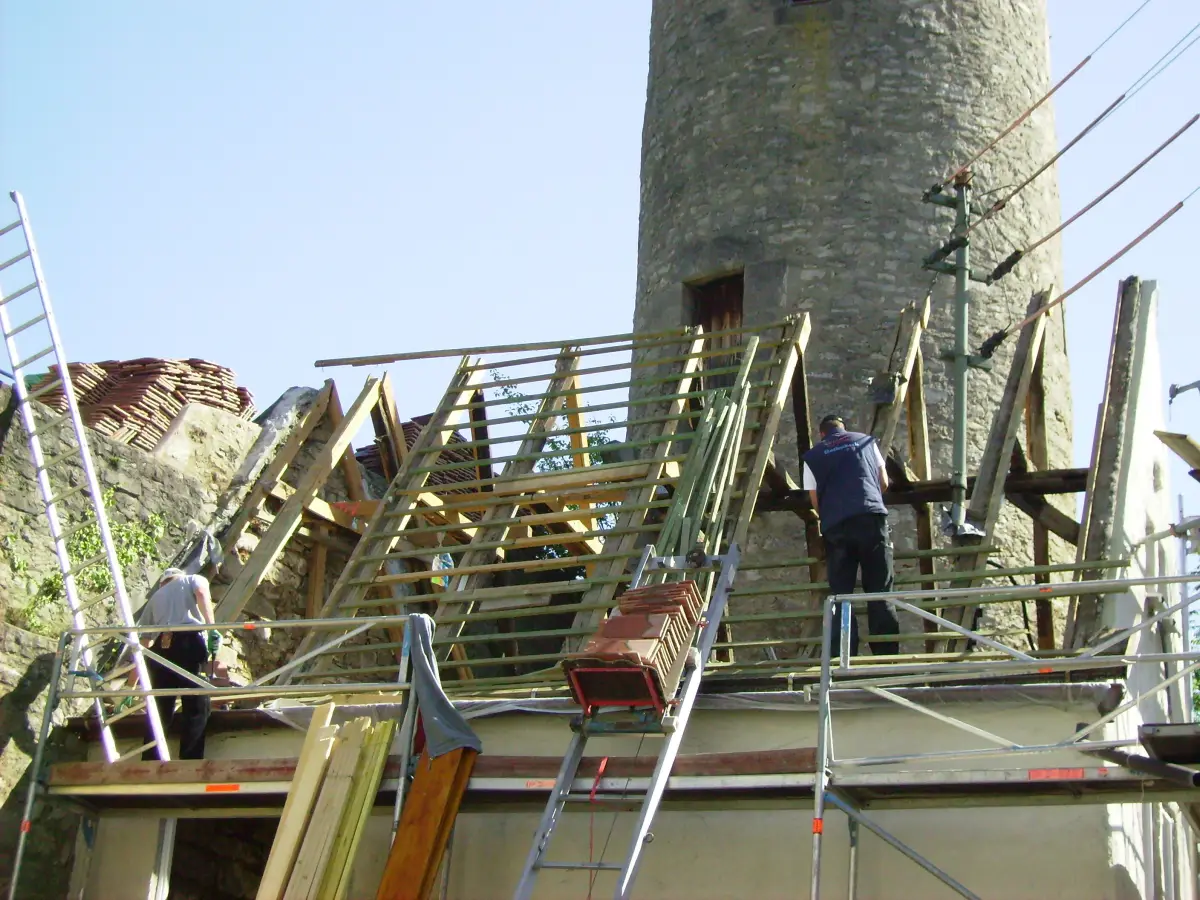 Zimmerer erneuern einen Dachstuhl neben einem alten Turm