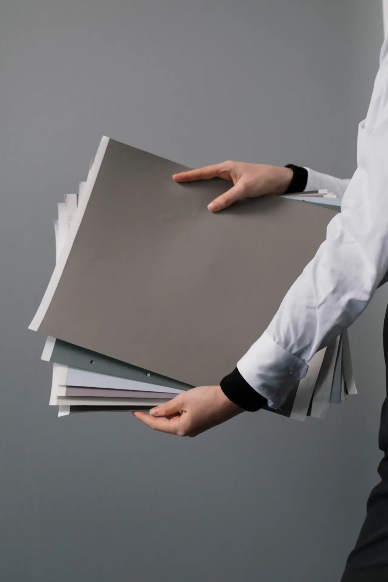 Hände tragen einen Stapel Mappen und Papiere
