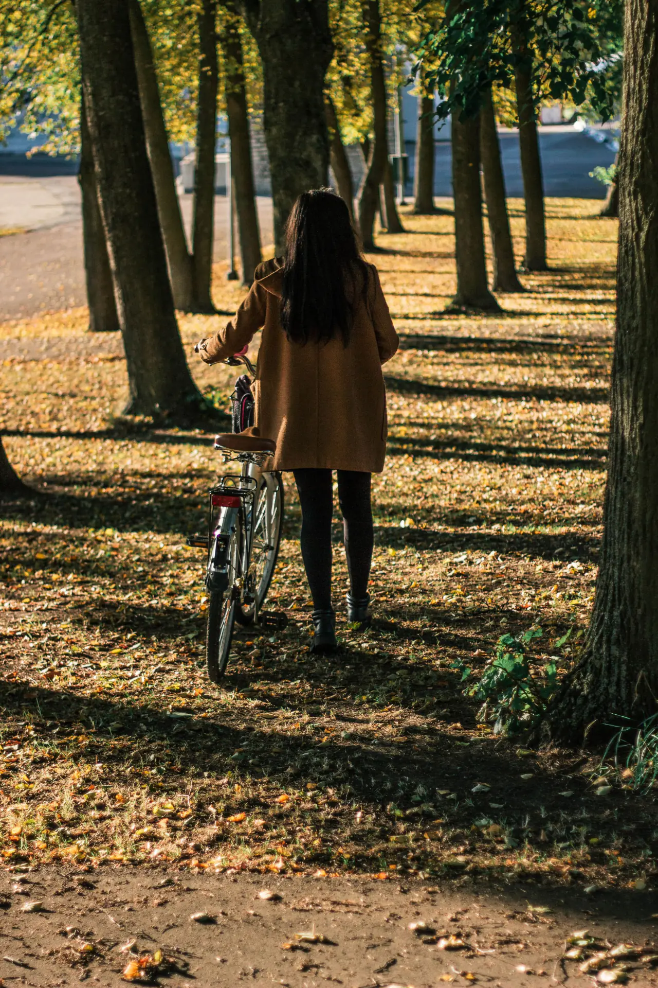 Eine Frau mit Fahrrad auf einer Straße, von hinten fotografiert